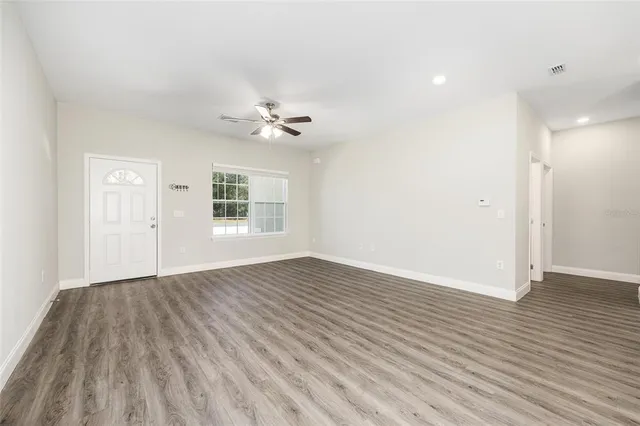 a view of an empty room with wooden floor and a window