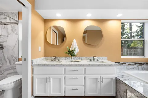 a bathroom with a granite countertop double vanity sink and a mirror