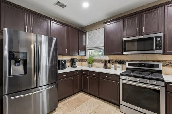 a kitchen with granite countertop a refrigerator stove and microwave