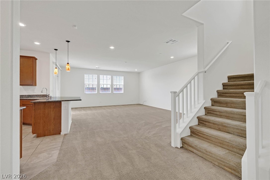 155 Fulgora Street Henderson, NV 89074 - Photo 29 of 30 An open floorplan seamlessly connects the kitchen with granite counters and pendant lighting to a carpeted living space.