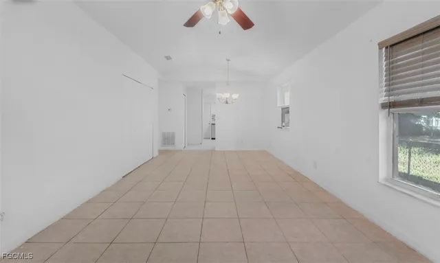 an empty room with chandelier fan