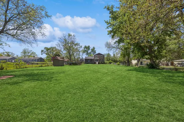 a view of grassy field with benches and trees all around