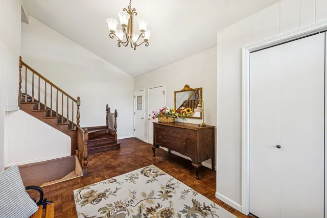 a view of a hallway with furniture and chandelier
