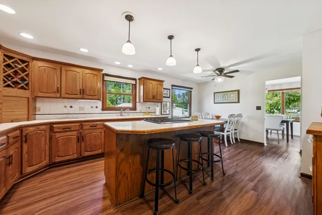 a kitchen with stainless steel appliances granite countertop wooden floors stove refrigerator and dining table with wooden floor