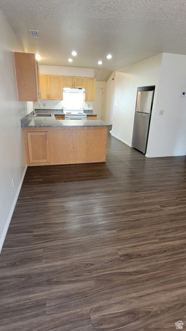 190 West 700 North Logan, UT 84321 - Photo 41 of 51 Kitchen featuring a peninsula, a textured ceiling, dark wood-type flooring, freestanding refrigerator, and electric stove