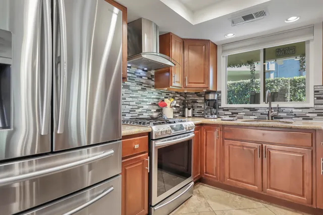 a kitchen with stainless steel appliances granite countertop wooden cabinets a sink and a large window