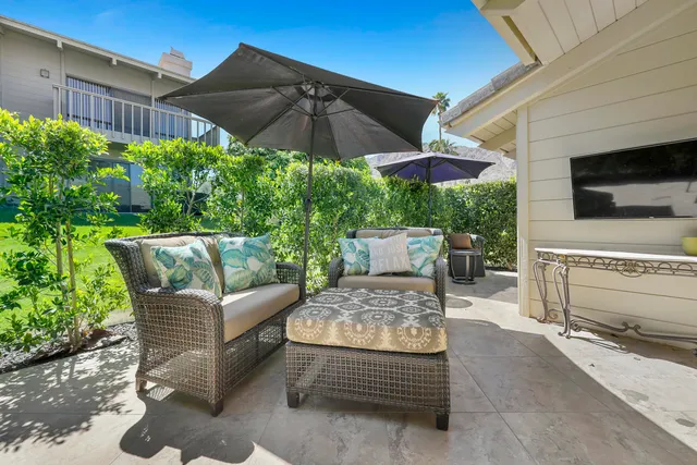 a backyard of a house with table and chairs under an umbrella