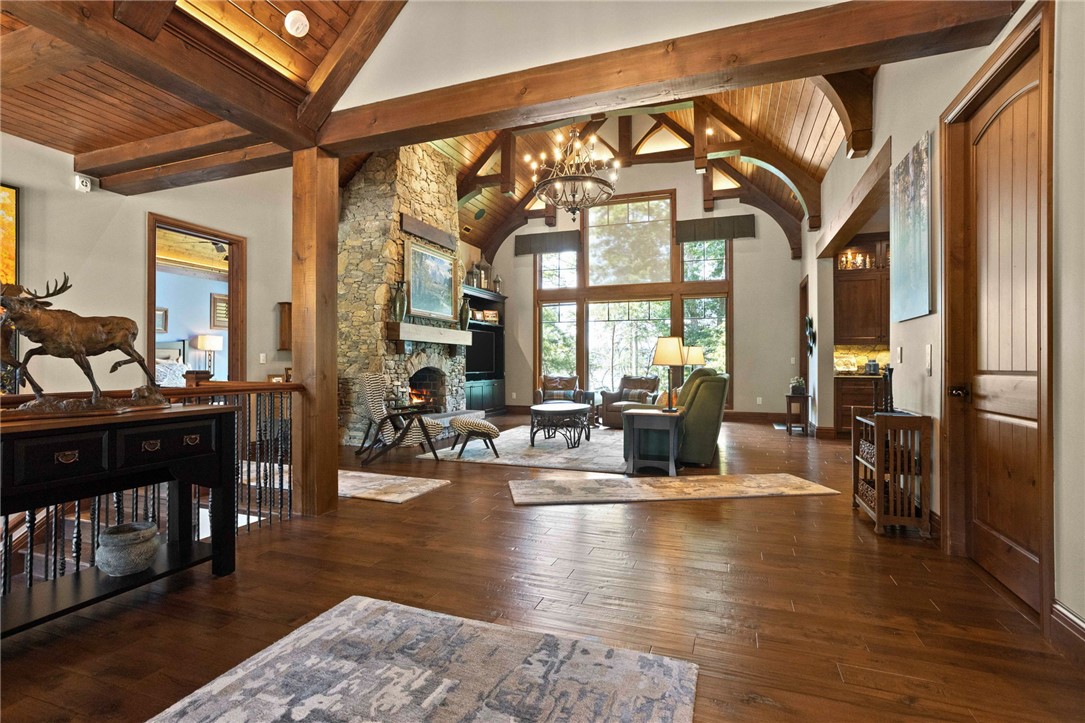 236 Palmer Way Sunset, SC 29685 - Photo 3 of 46 Natural wood floors complement a stone fireplace and vaulted ceilings in this grand living room, framed by expansive windows.