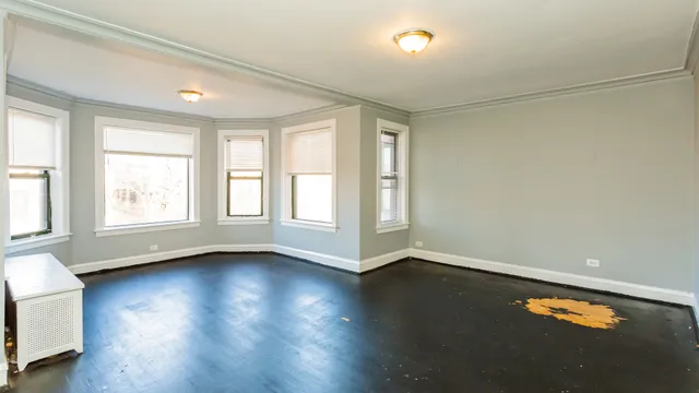 an empty room with wooden floor and windows with curtains