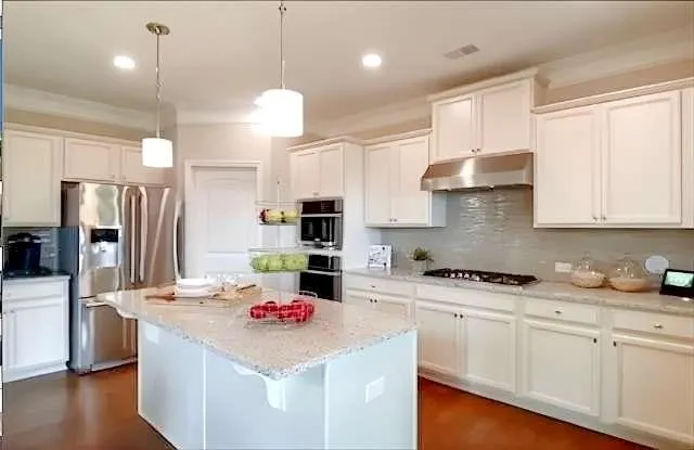 a kitchen with stainless steel appliances kitchen island granite countertop a sink stove and refrigerator