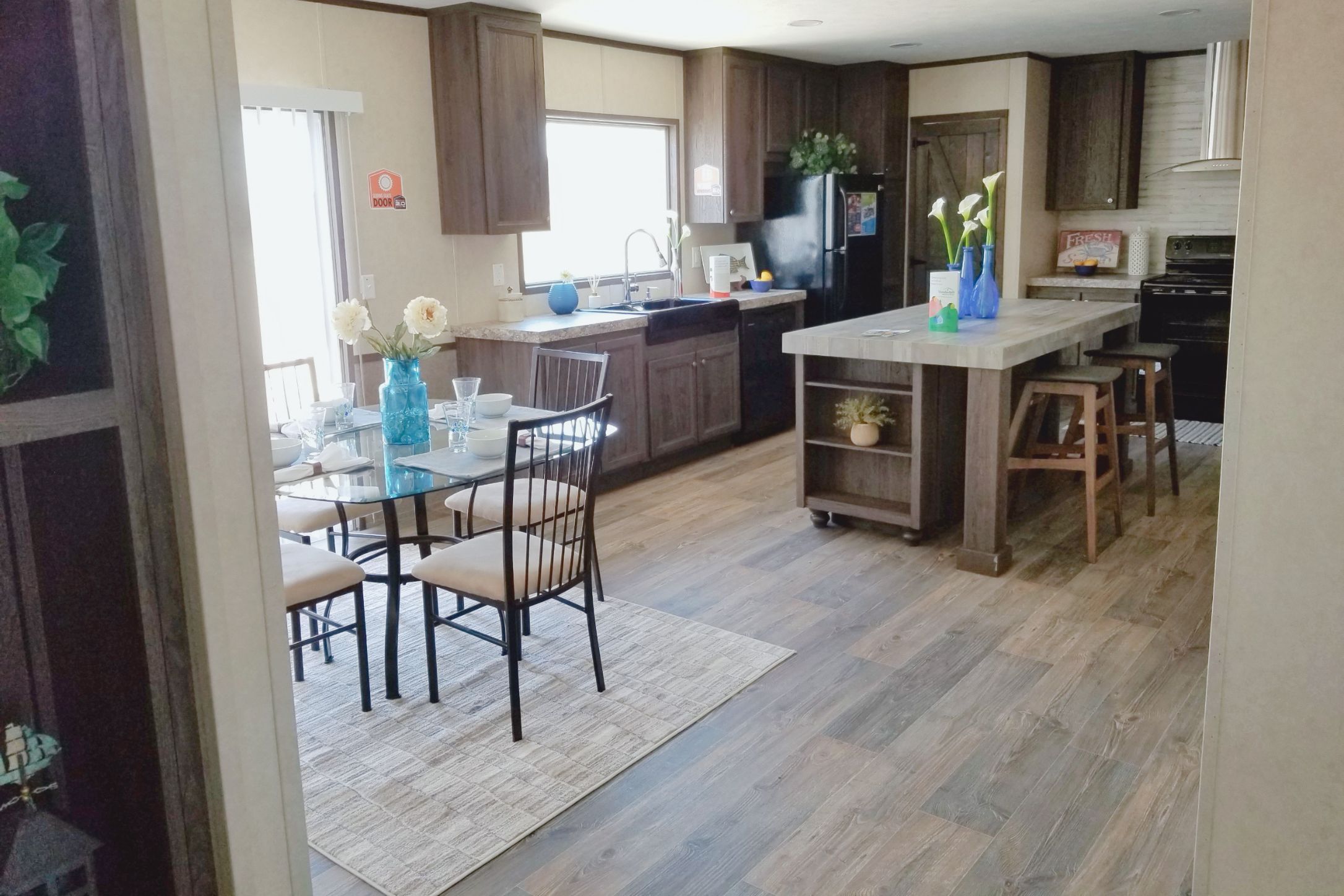 2409 County Road 313 Jarrell, TX 76537 - Photo 6 of 14 Kitchen featuring tile counters, black appliances, a kitchen island, light wood-style flooring, and a kitchen bar