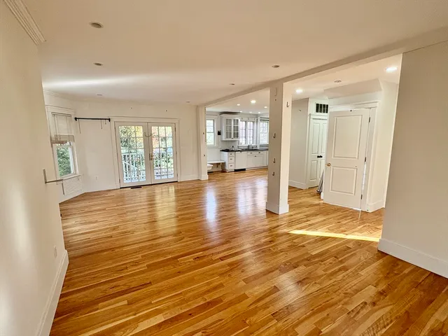 a view of an empty room with window and wooden floor