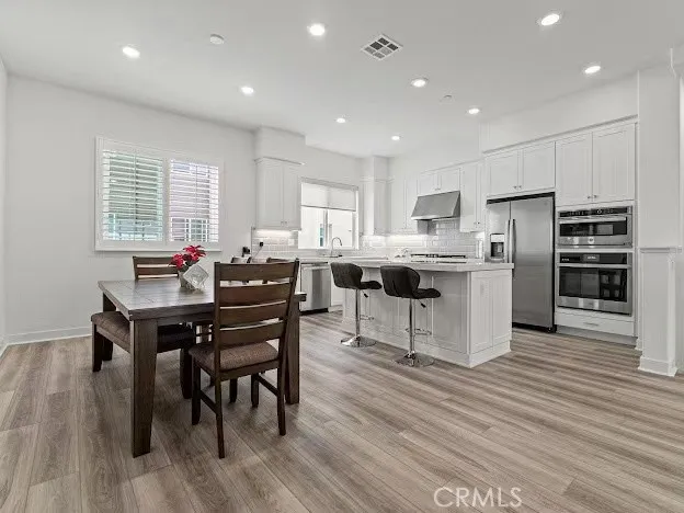 a kitchen with stainless steel appliances kitchen island granite countertop a table chairs sink refrigerator and cabinets