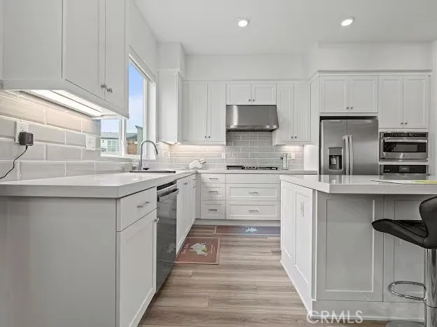 a kitchen with kitchen island white cabinets appliances and a sink