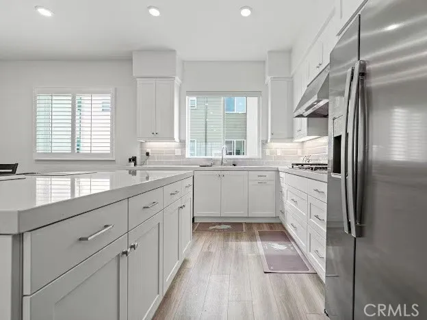 a kitchen with white cabinets appliances a sink and a window