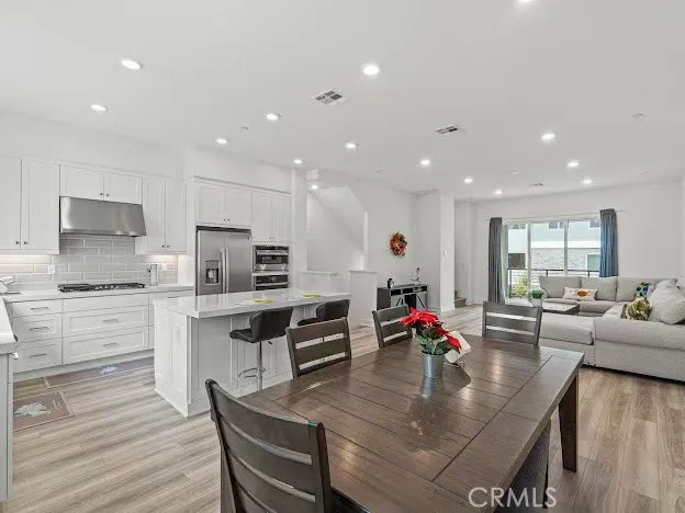 a large kitchen with granite countertop lots of counter space white cabinets and stainless steel appliances