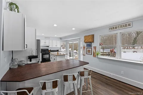 a kitchen with stainless steel appliances granite countertop a stove a refrigerator a sink a dining table and chairs with wooden floor