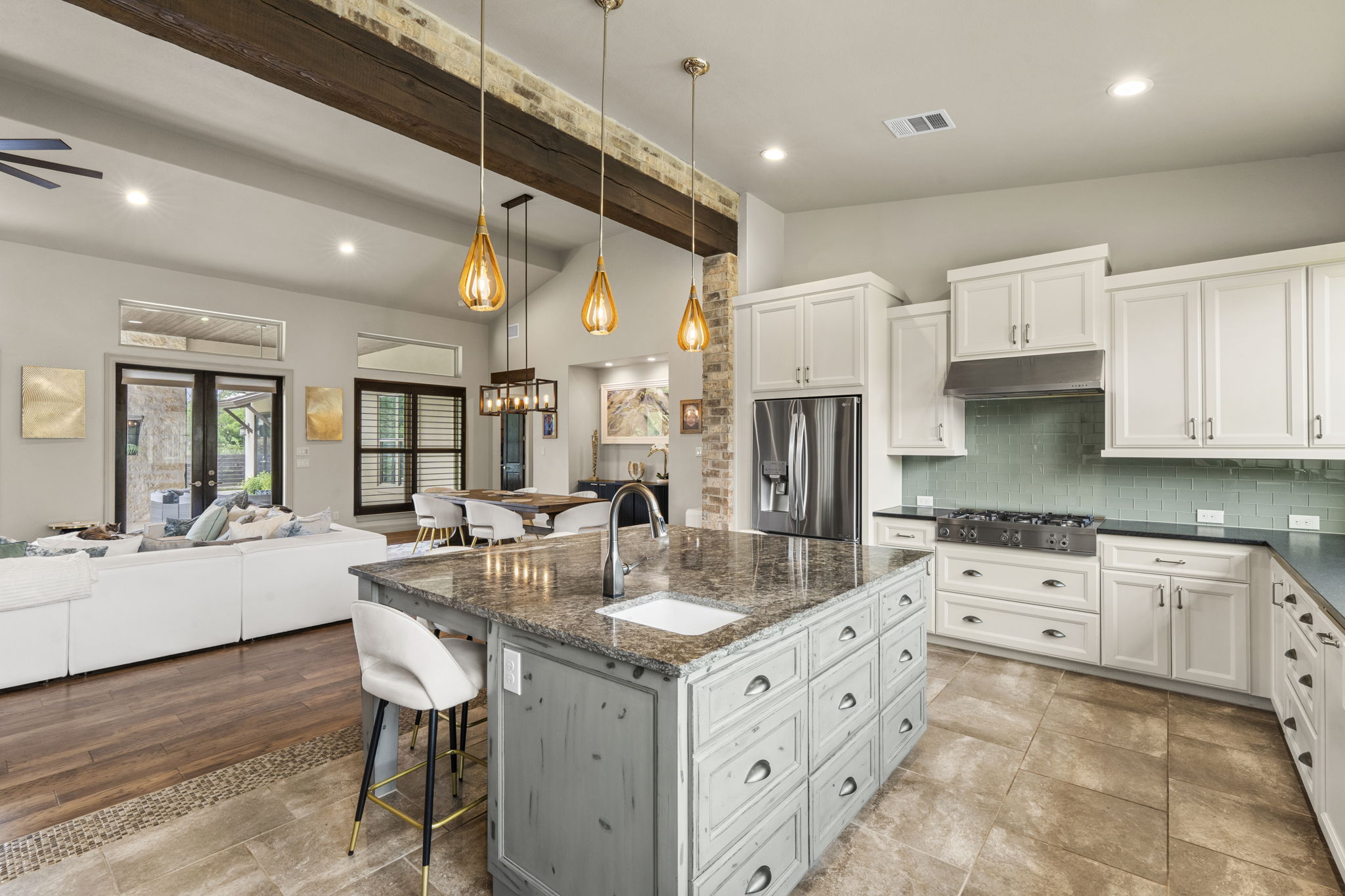 16202 Remuda Trail Buda, TX 78610 - Photo 10 of 40 Open-concept living space featuring a kitchen with a large island, white cabinetry, and stainless steel appliances, alongside a dining area and living room with wood flooring