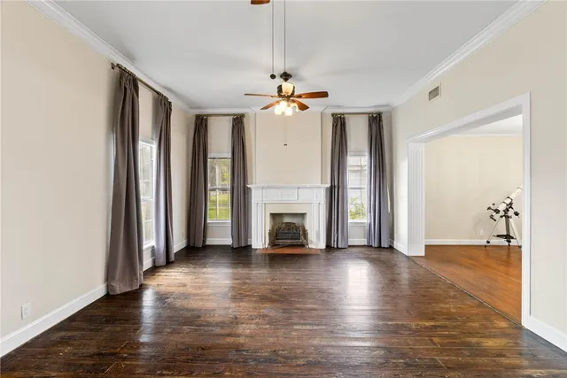 an empty room with wooden floor a chandelier fan and windows