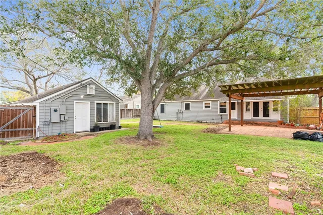 a view of a house with a small yard and a large tree
