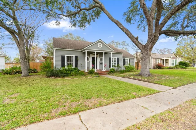a front view of a house with a garden and trees