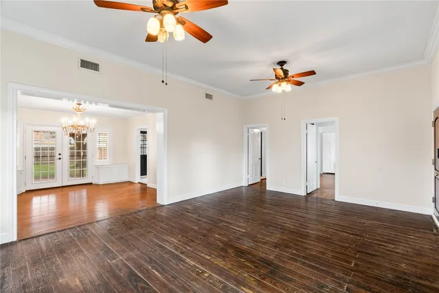 a view of an empty room with window and wooden floor