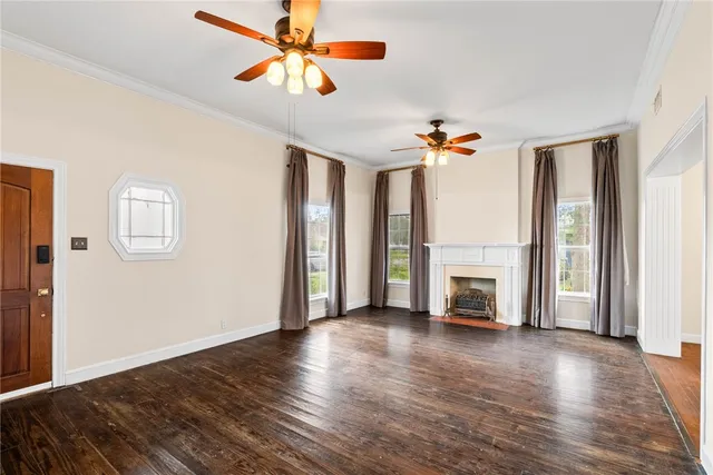 a view of a livingroom with a fireplace a ceiling fan and wooden floor