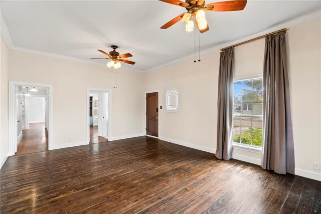 a view of an empty room with window and wooden floor