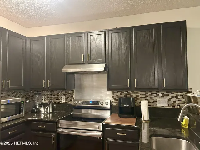 a kitchen with granite countertop a stove and cabinets