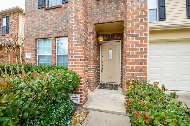 a view of a brick house with a large windows and flower plants