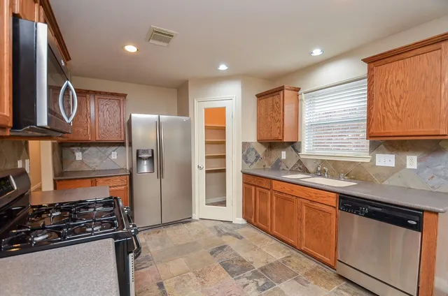 a kitchen with stainless steel appliances granite countertop a stove a refrigerator and a sink