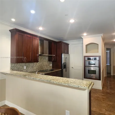 a kitchen with granite countertop a refrigerator and a sink