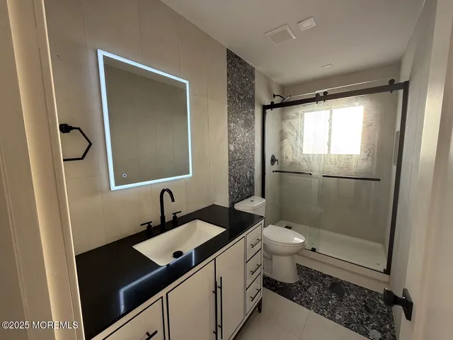 a bathroom with a granite countertop sink toilet and shower