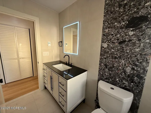 a bathroom with a granite countertop toilet and a sink