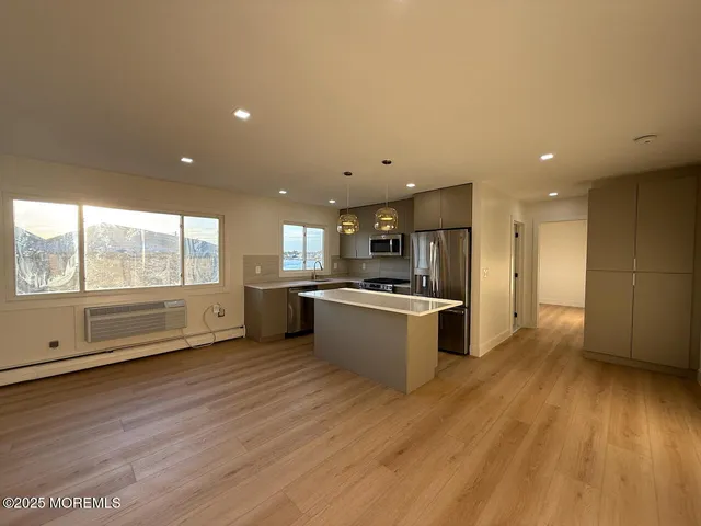 a large kitchen with a large counter top a sink stainless steel appliances and cabinets