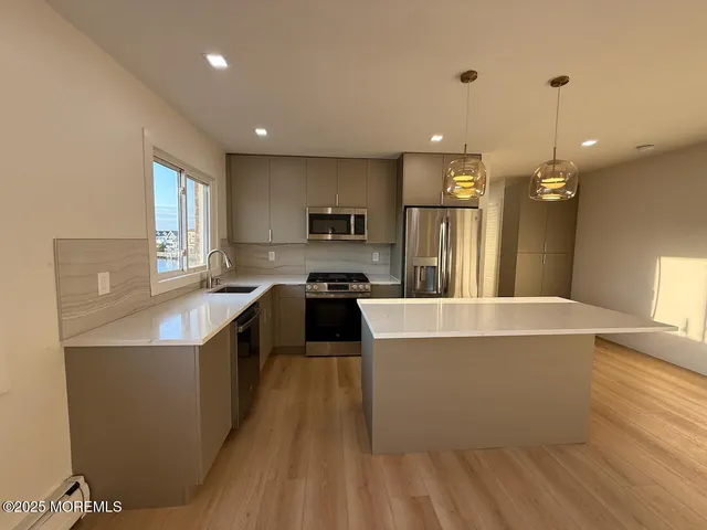 a large kitchen with stainless steel appliances granite countertop a sink a stove and a refrigerator