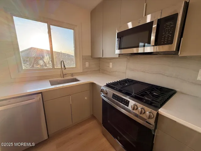 a kitchen with stainless steel appliances a stove a sink and a microwave