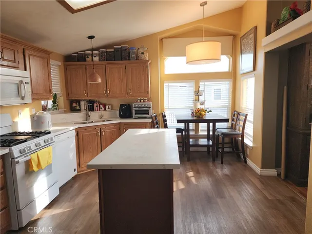 a open kitchen with stainless steel appliances granite countertop a stove top oven a sink a dining table and chairs