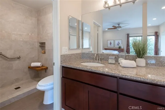 a bathroom with a granite countertop sink a toilet and a mirror