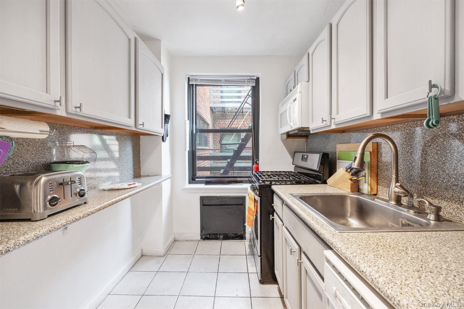 75-20 Bell Boulevard, Unit 5A Queens, NY 11364 - Photo 7 of 7 a kitchen with stainless steel appliances granite countertop a sink stove and cabinets
