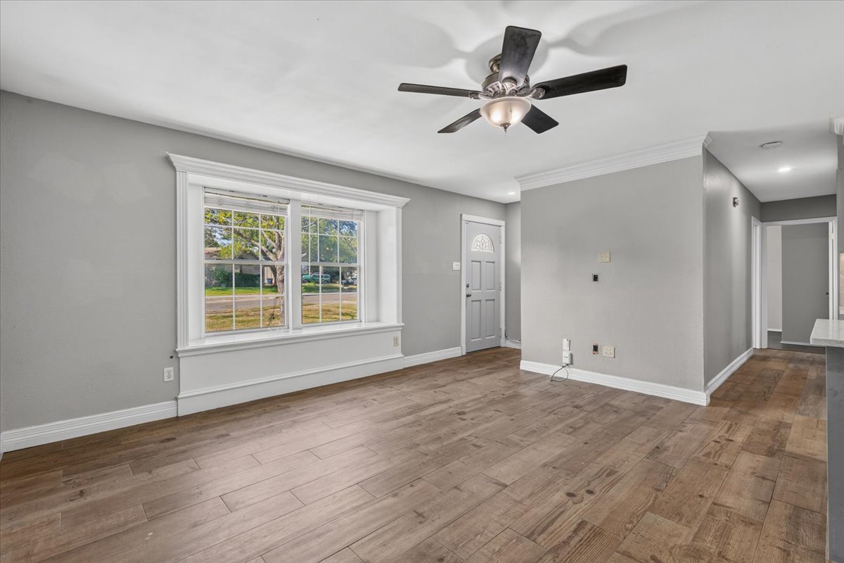 6200 Shadow Bend Austin, TX 78745 - Photo 3 of 33 A well-lit living area features warm wood flooring, crisp crown molding, and a stylish ceiling fan.