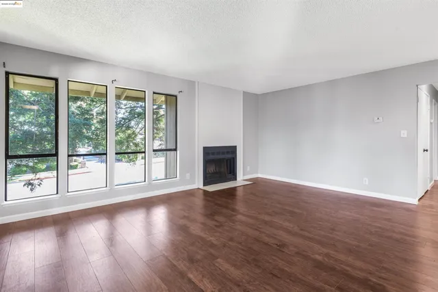 a view of empty room with wooden floor and fireplace