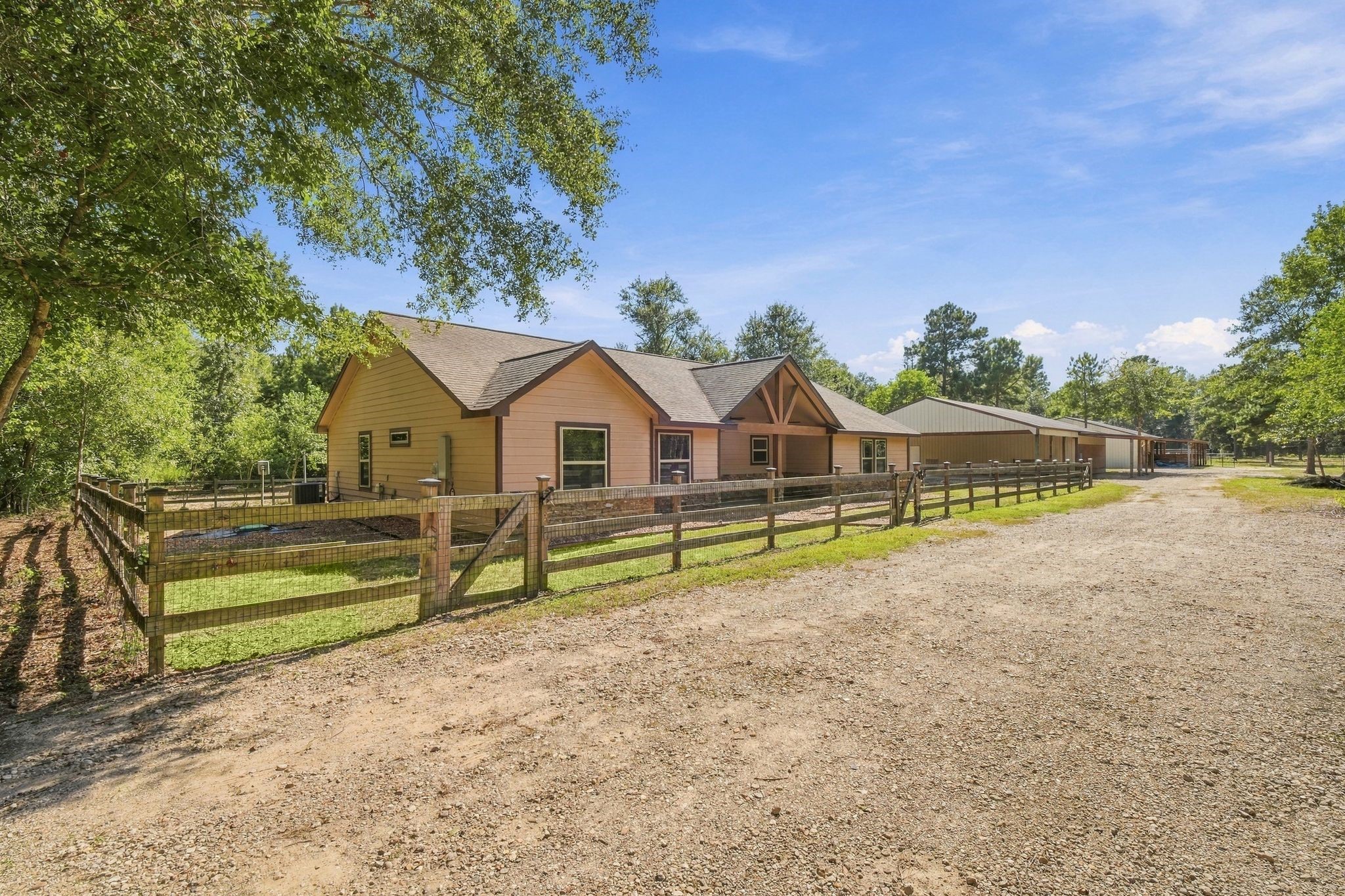 7049 Pine Shadows Road Cleveland, TX 77328 - Photo 3 of 49 Charming country home with a spacious yard, surrounded by a wooden fence and nestled among lush trees, offering a serene rural retreat.
