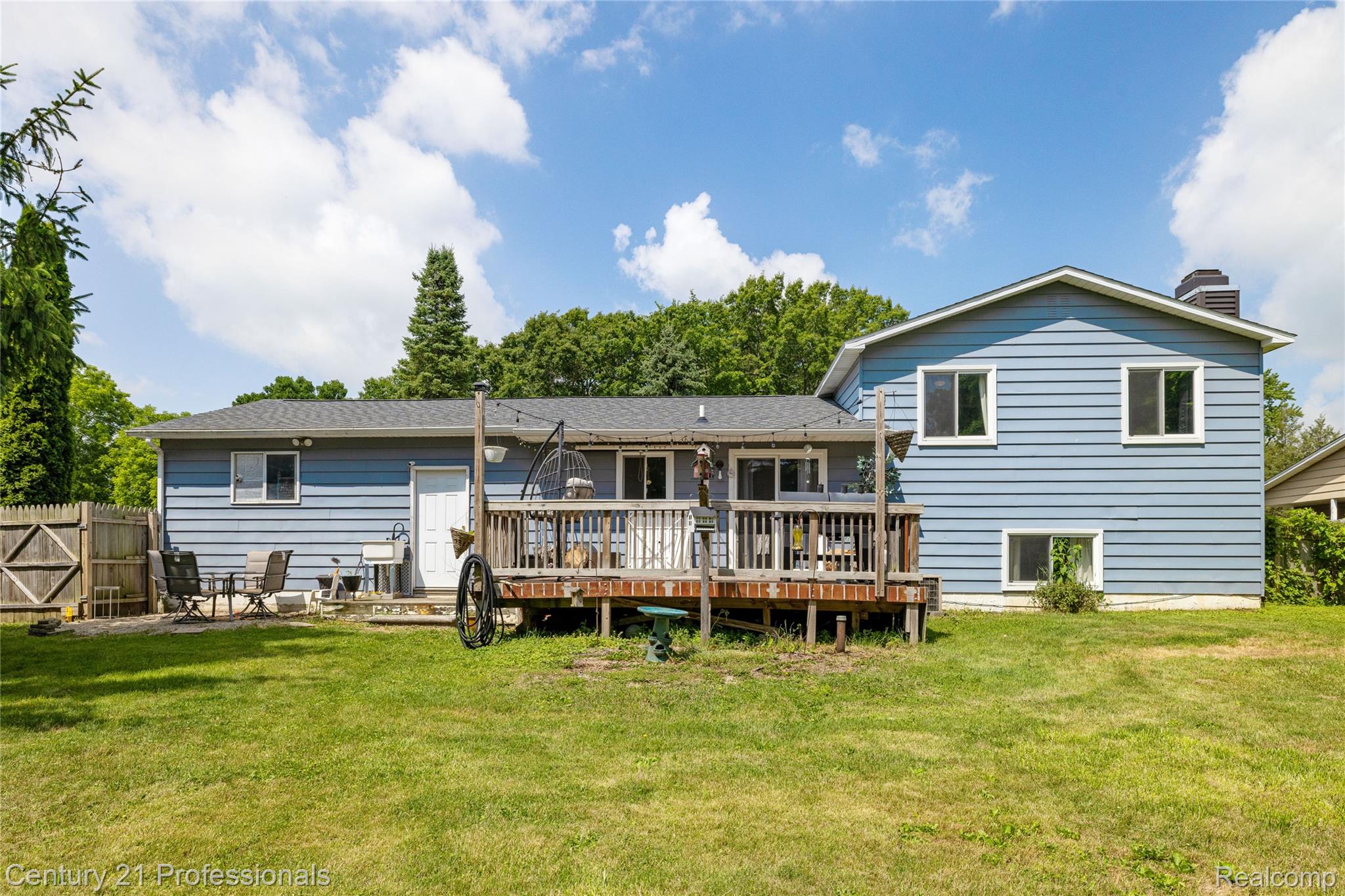 15037 Hogan Road Linden, MI 48451 - Photo 36 of 38 Backyard with a wood deck, expansive lawn, and partial privacy fencing