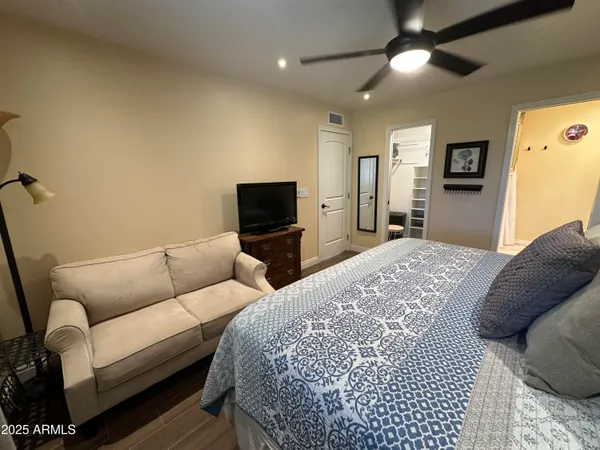 a bedroom with a bed a couch and a flat screen tv