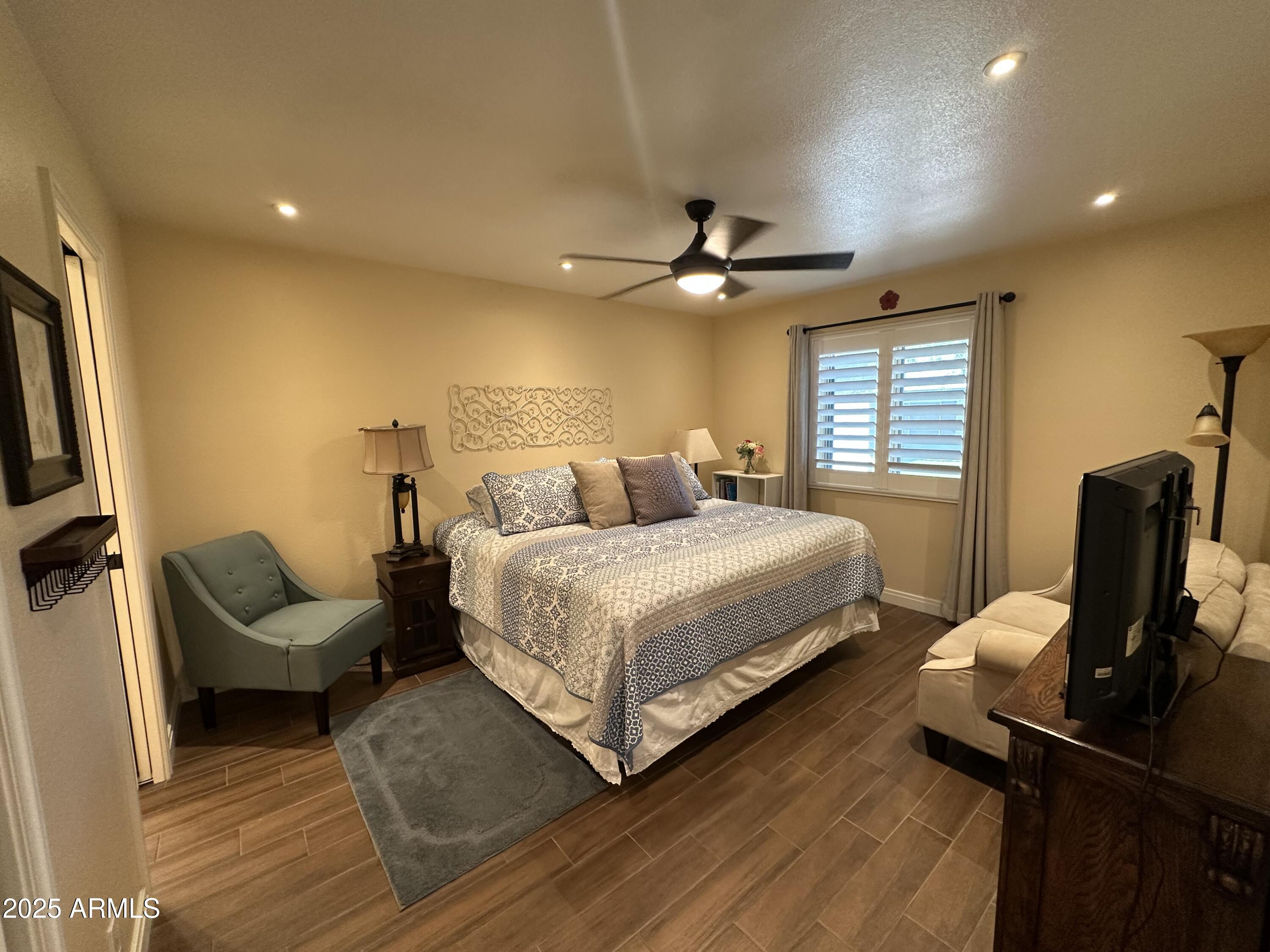 4328 East Capri Avenue, Unit 180 Mesa, AZ 85206 - Photo 31 of 38 a bedroom with a bed a couch and a flat screen tv