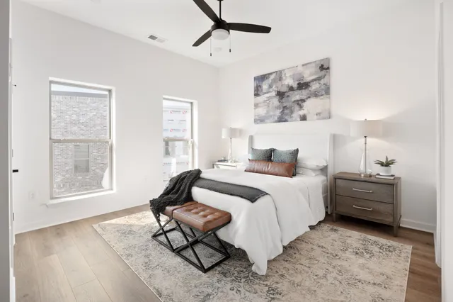 a bedroom with a bed large window with wooden floor