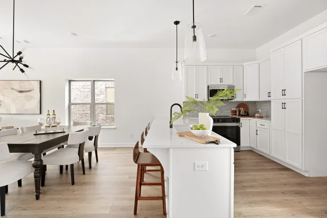 a kitchen with stainless steel appliances kitchen island granite countertop a stove a sink a dining table and chairs
