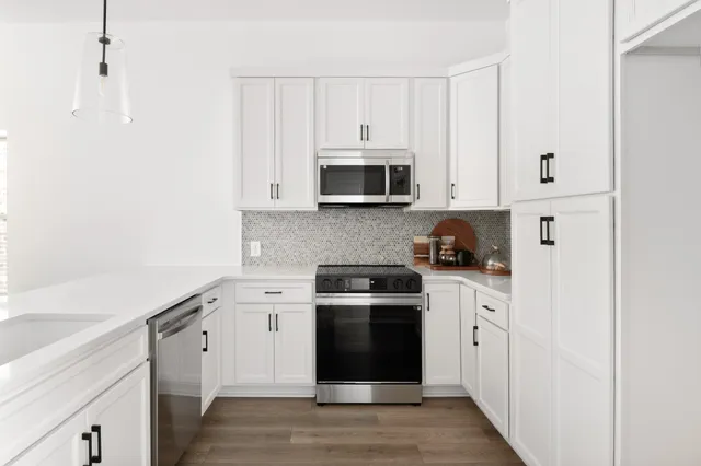 a kitchen with granite countertop white cabinets and stainless steel appliances