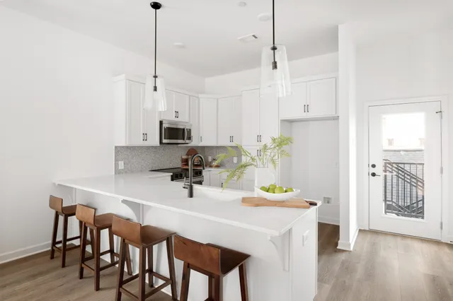 a kitchen with kitchen island a stove a table and chairs in it